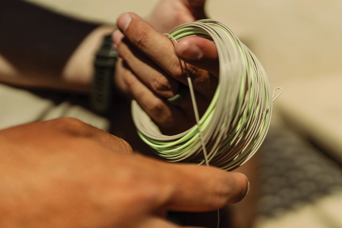 Close-up of hands holding a spool of green and white fly line